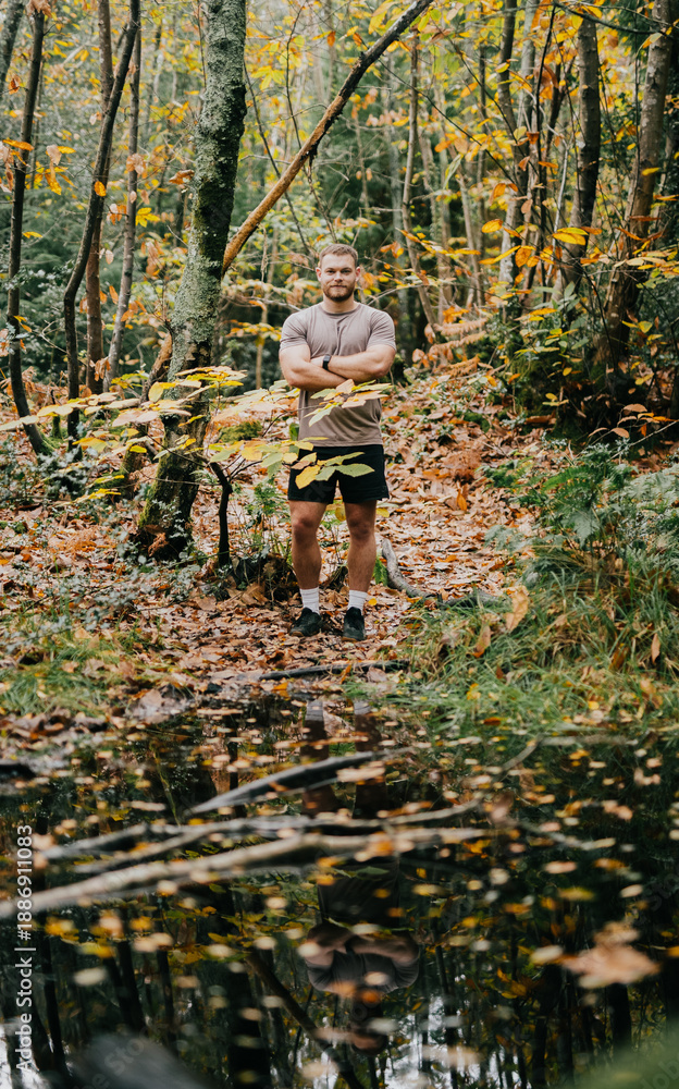 Obraz premium A man stands in a forest with his arms crossed