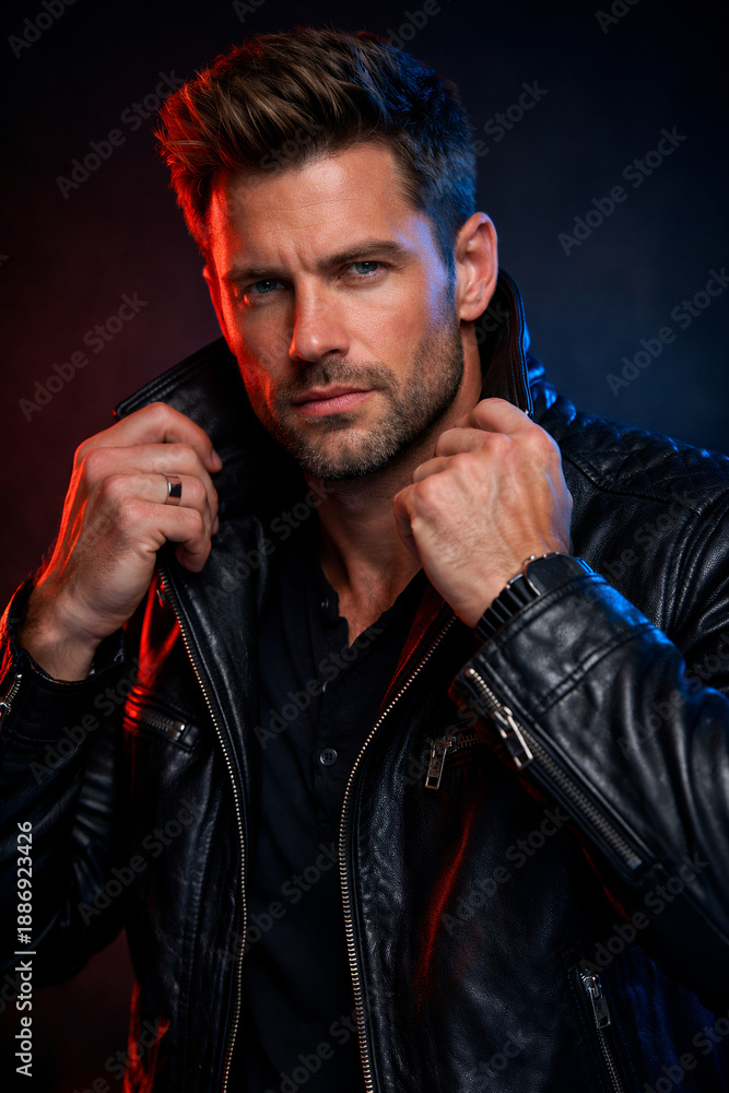 Obraz premium Intense Man Holding Leather Jacket Collar Under Dramatic Red and Blue Lights