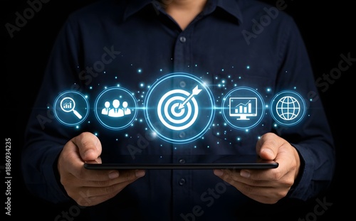 Wallpaper Mural Person holding a tablet showing a glowing target icon surrounded by business strategy and goal-setting symbols. Torontodigital.ca