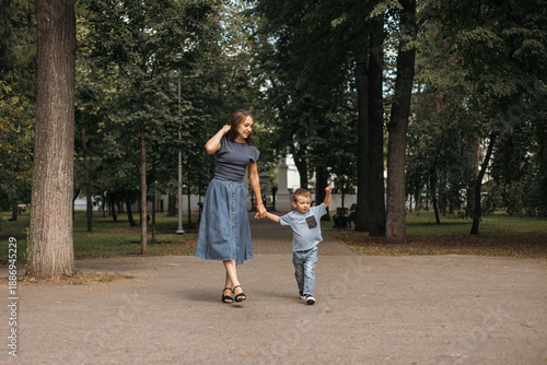 A happy young mother plays and has fun with her little son outdoors in a park. The mother talks to her baby. The concept of a happy family and motherhood. A mother taking a walk with her little child.