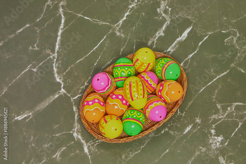 Easter eggs in a rustic wicker basket on a marble background. Easter egg hunt concept.