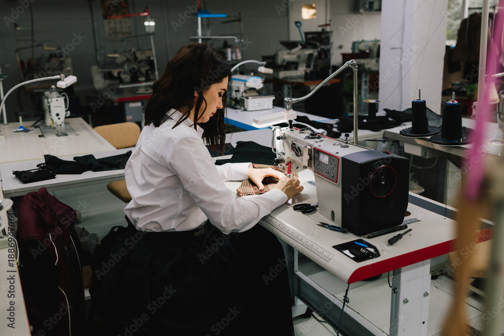 Naklejka premium Designer operates sewing machine, transforming raw fabric into stylish garments and apparel.