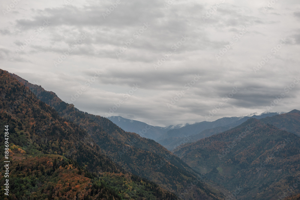 Fototapeta premium Autumn mountains stretch across dramatic valley under clouds