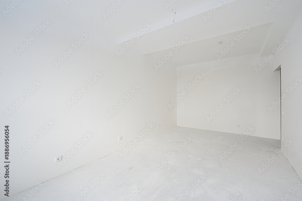 Obraz premium spacious, empty room with white walls and floor, minimalist design, one radiator, recessed ceiling lights, a doorway leading to another space, no furniture, clean and bright.