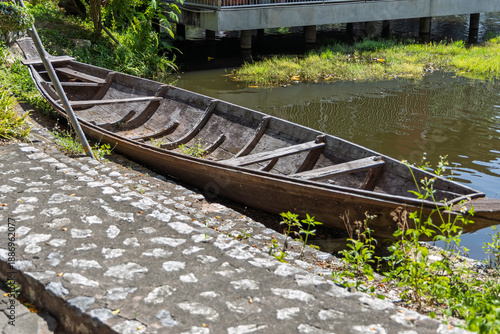 Old wooden boat resting on stone embankment near water under bridge at The Million Years Stone Park Pattaya Thailand