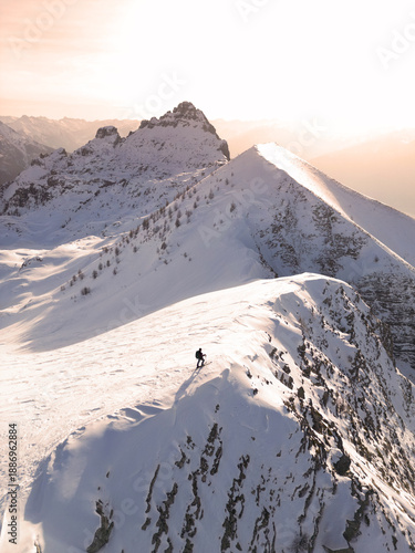 Obraz na plátně Hiker on Top Snowy Mountain Ridge at Golden Hour