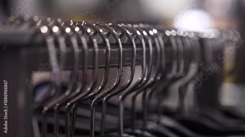 Clothing hangers macro close-up video of empty metal clothes hangers aligned on a rack. Shallow depth of field, retail store atmosphere, minimalist fashion and shopping concept.