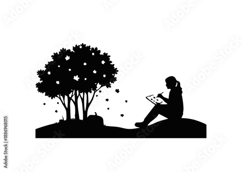 Silhouette of a person sitting outdoors on a hill, drawing on a tablet, with a tree and fallen leaves in the background