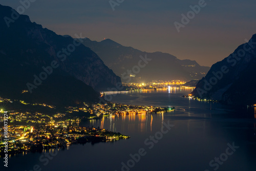 Wallpaper Mural A breathtaking nocturnal panorama of a lakeside town nestled between majestic mountains, illuminated by a warm glow Torontodigital.ca