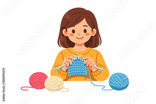 Young woman knits a blue piece of fabric using knitting needles while sitting at a table with colorful yarn balls during a crafting session at home