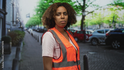 Foto Woman in reflective safety vest standing on street looking to the side with a serious expression; determination