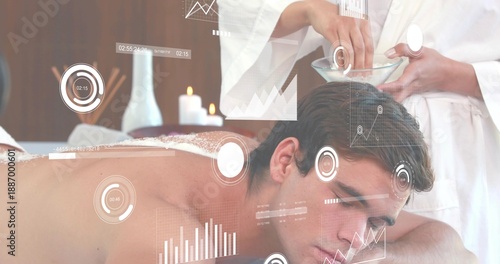 Client lying prone in spa with white towel, therapist in white robe prepping glass bowl, HUD