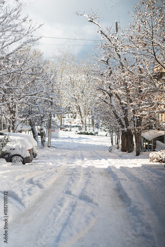 Winter city street. Roads, sidewalks, trees, and parked cars are heavily covered in snow. A sunny January day. After a heavy overnight snowfall. New Year's Morning. Old houses. An empty road.