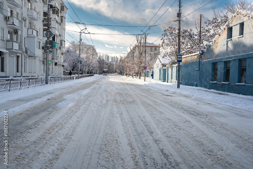 Winter city street. Roads and sidewalks are covered with snow. A sunny January day. After a heavy overnight snowfall. New Year's Morning. Old houses. One bus. The road is almost empty.