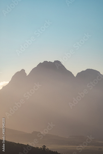 Misty mountain landscape at sunset with soft light. Morning fog over a tranquil valley and hills. Copy space for nature concept.