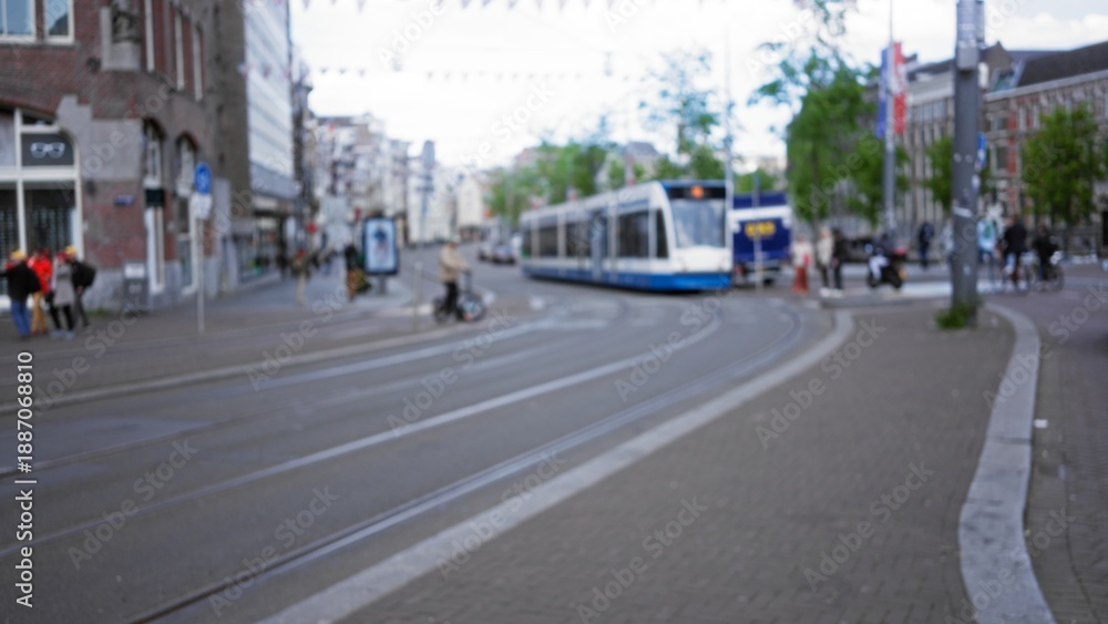 Obraz premium Blurred street scene in an amsterdam cityscape with tram and pedestrians in out-of-focus background for urban travel settings.