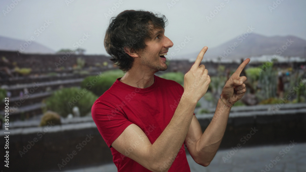 Fototapeta premium Man finger pointing in sunlit green park at ancient stone ruins with wide grin and open mouth; enthusiasm.