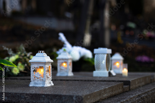 Lit burning candle at night on black stone monument in cemetery. Memory of the deceased. Expression of love