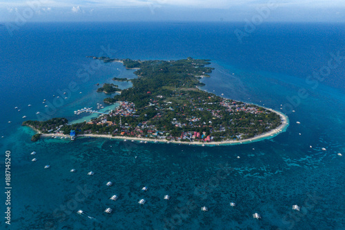 High Angle Drone Shot of Malapascua Island Surrounded by Vibrant Coral Reefs and Deep Blue Sea.