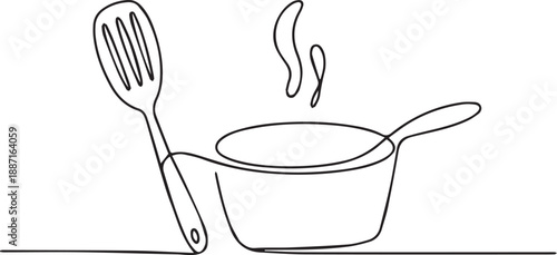 A steaming saucepan with a utensil beside it on a surface viewed from the side