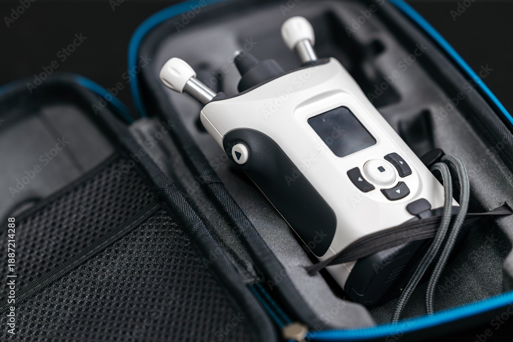 Obraz premium Portable electronic device with buttons and display placed inside a protective carrying case, featuring a mesh pocket for accessories and a blue zipper