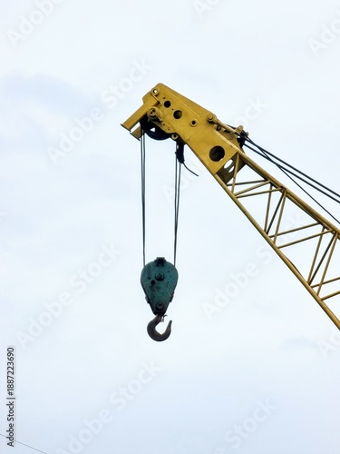 Yellow construction crane hook against white sky