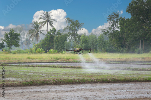 A drone effectively sprays pesticide over a farm field surrounded by lush green trees.