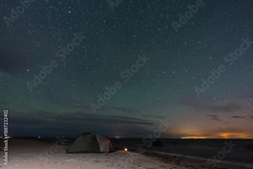 Obraz na plátně Night sky astrophotography of a lit tent on a sandy Baltic Sea beach in Estonia under a starry landscape background