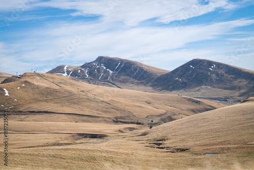 Wide mountain landscape of rolling golden hills and distant mountains in Bucegi National Park, Romania