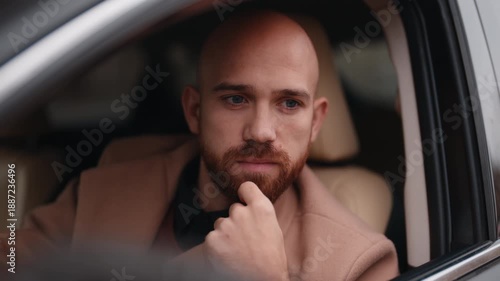 Thoughtful Bald Man with a Beard Sits Pondering in His Car