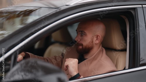 Happy Bald Man with a Beard Smiles and Gestures Playfully While Sitting in His Modern Car