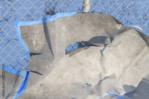 abstract torn synthetic material wind blown up against a fence outdoors