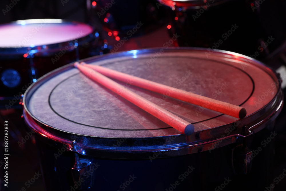 Obraz premium Wooden drumsticks on drum in color light, closeup