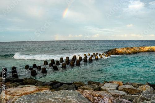 Wallpaper Mural Visit to Fuvahmulah Island in the Maldives showing a rocky shoreline with waves and a rainbow in the sky during the day Torontodigital.ca