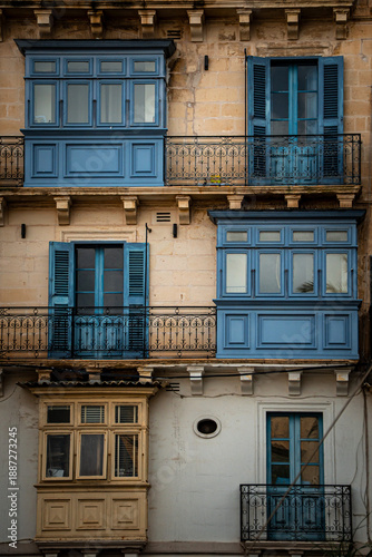Detailed view of traditional enclosed balconies in Valletta, Malta—blue and beige woodwork on stone facade