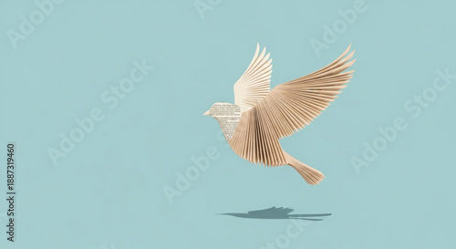 Brown bird in flight with spread wings against light blue background with shadow