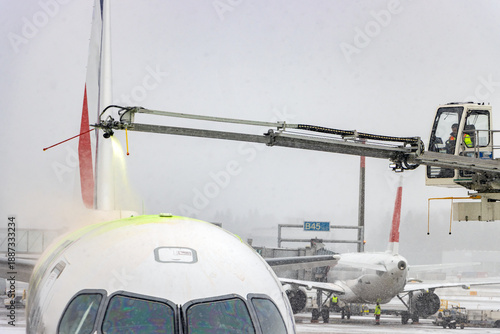De-icing An Aircraft On The Ground With An Elevated Arm In Snow At The Airport