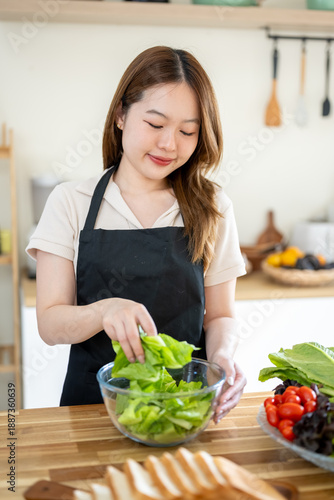 An Asian woman is making a salad in the kitchen. The concept is related to healthy eating and dieting.
