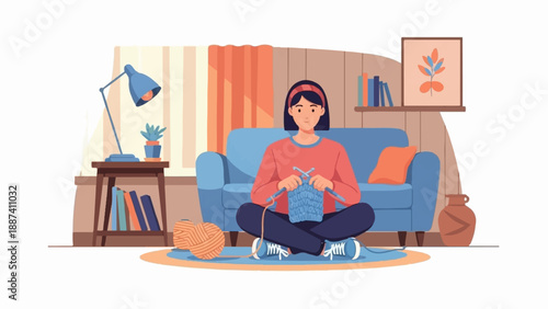 Person knitting a blue fabric sitting cross-legged on a rug