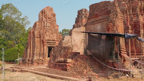 Wide view of ancient brick temple ruins with damaged walls and restoration covering at Angkor Wat in Cambodia, showing historic architecture, preservation work, and heritage