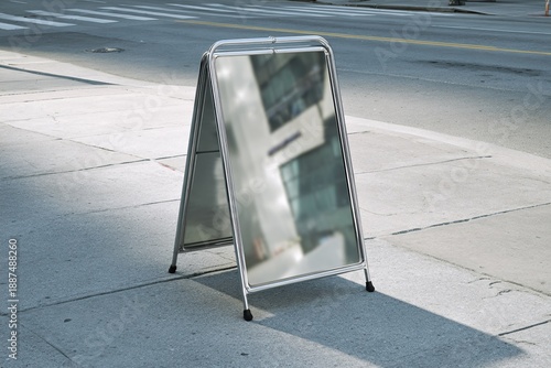 Blank sidewalk sign on street corner with modern building reflection