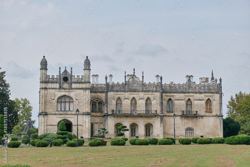 Fototapeta premium Mansion manor historic architecture stone facade estate landscape with detailed windows and turrets isolated building on lawn under cloudy sky preserved exterior masonry