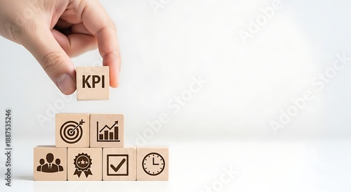 Hand places KPI block on top of wooden cubes with business icons, emphasizing key performance indicators for business success.