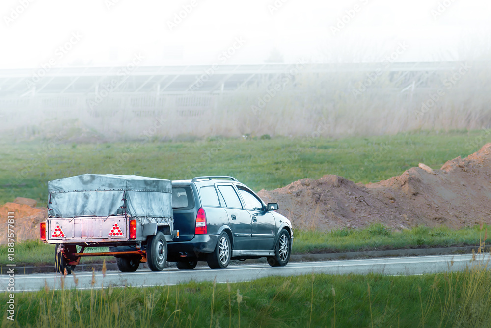 Fototapeta premium Car and trailer driving past construction