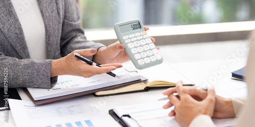 Smiling asian businesswomen financial advisor explaining financial result showing calculator to client or Collegue  in meeting.
