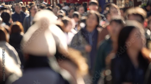 Blurred crowd of people walking on a bright sunny day in Tokyo.