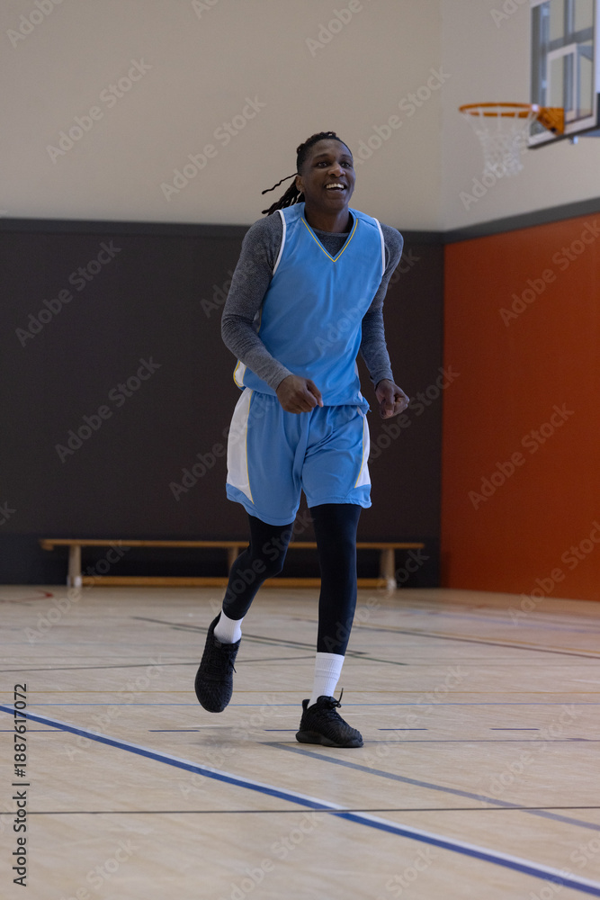 Fototapeta premium Basketball hoop and backboard are hanging on orange wall above hardwood court, bench visible
