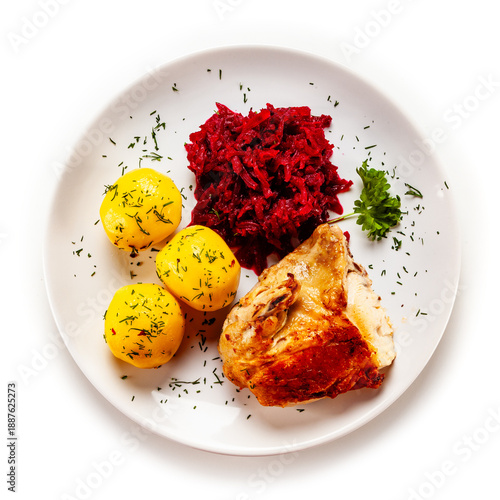 Roasted chicken quarter with boiled potatoes and beetroot salad on white background. Top view