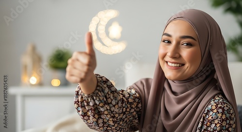 Smiling Muslim woman wearing hijab giving a thumbs up gesture.