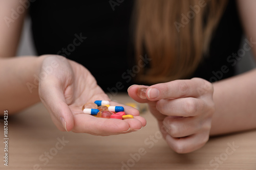 фотографія A woman takes dietary supplements, various colored capsules and tablets in her h